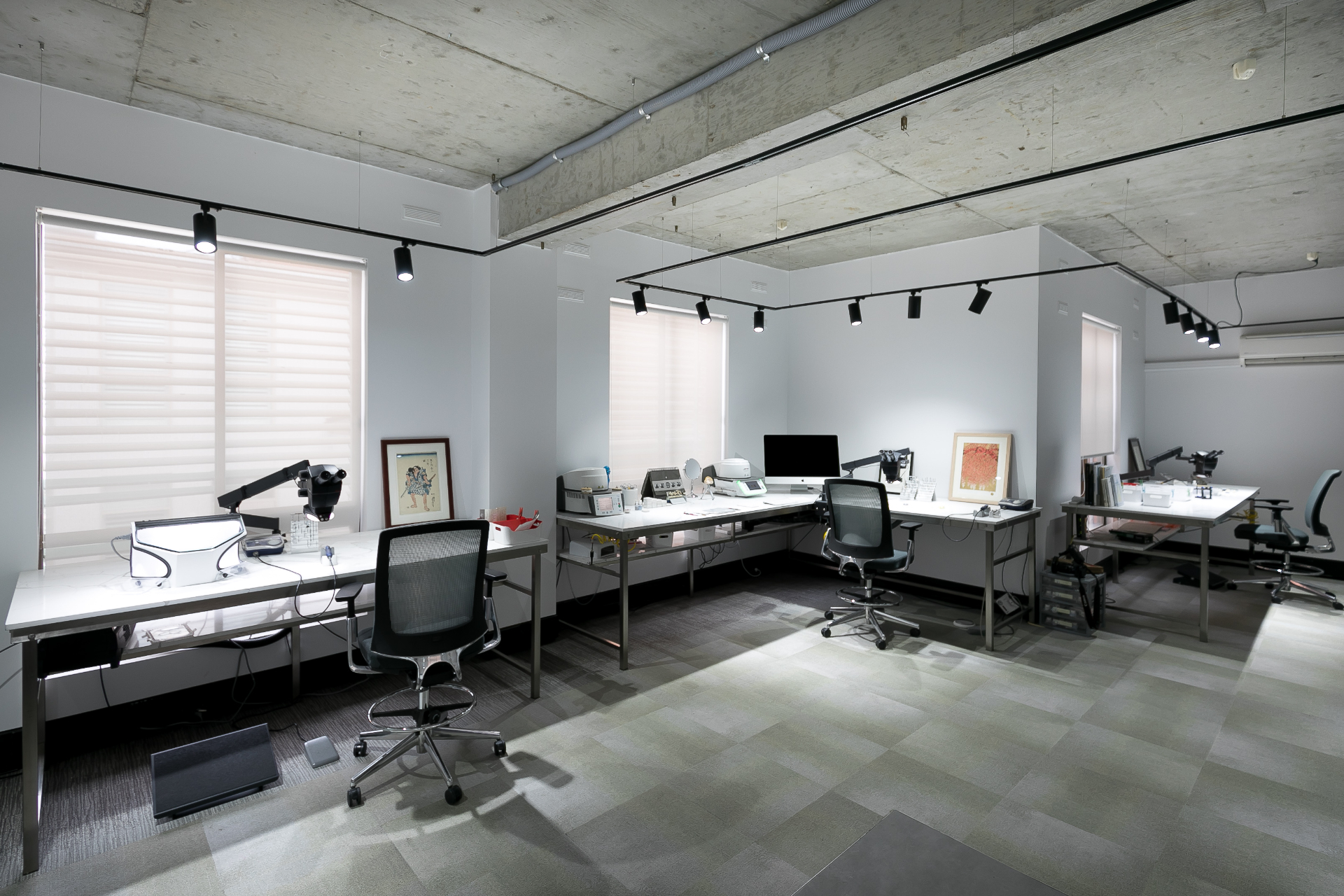 Three workstations arranged across the studio with equipment and framed artwork